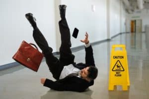 A man slips on a wet floor and falls on his back