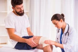 A Doctor examines a patient's injured knee.