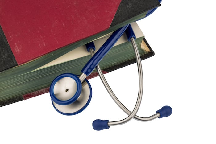 A stethescope rests between the pages of a closed book