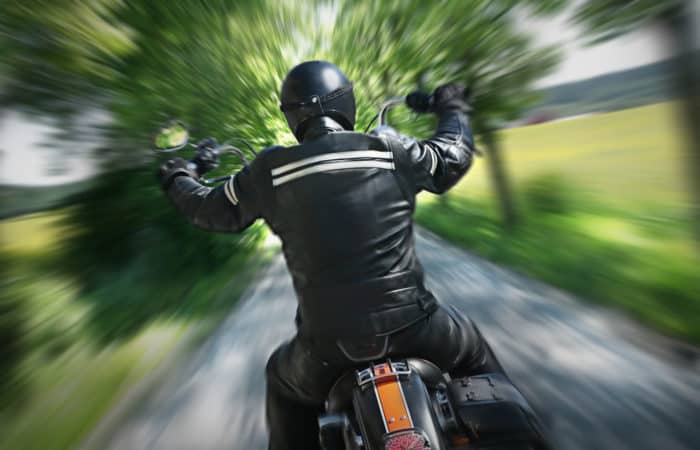 A motorcycle rider speeds down a country road