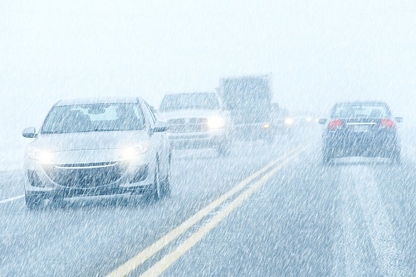 Traffic moves slowly along a busy road during a heavy sleet storm
