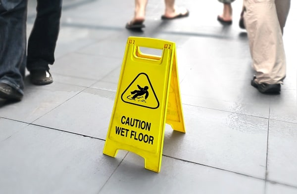 Wet floor sign with people walking in background