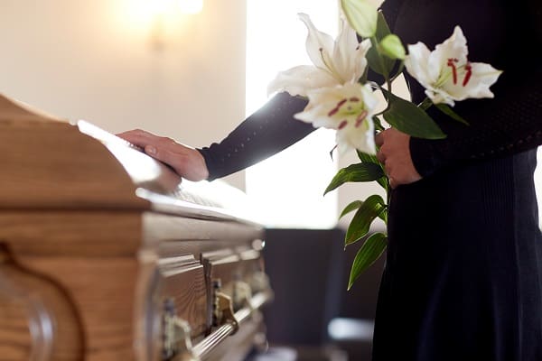 A woman with white lily flowers and coffin at funeral in church