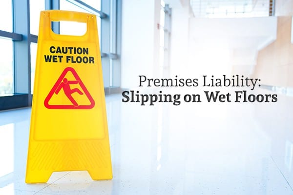 A wet floor sign sits on a floor beside the words "Premises Liability: Slipping on Wet Floors"