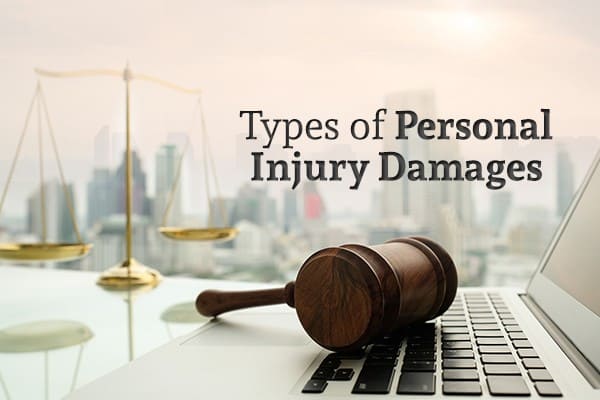 A gavel sits on a laptop in front of a city skyline and words Types of Personal Injury Damages