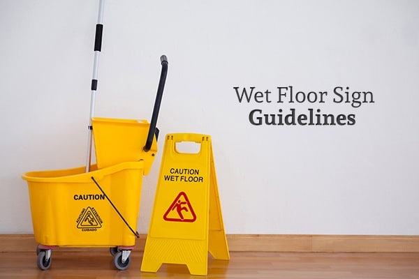 A mop and bucket beside a wet floor sign on a wood floor, along with the words "Wet Floor Sign Guidelines"