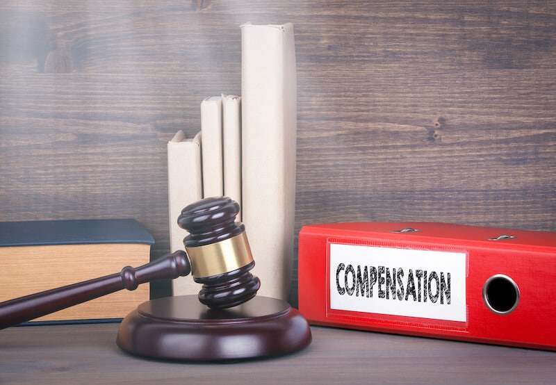 court gavel beside binder with the words "compensation"