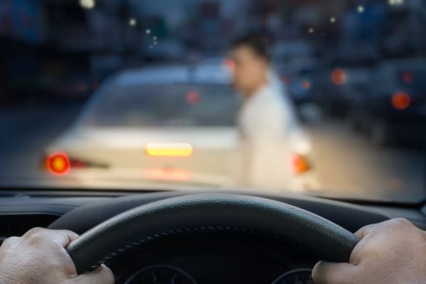 A pedestrian is crossing the street and a driver is approaching them.