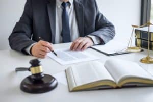 A lawyer going over legal documents with a book, gavel, and a set of legal scales. 