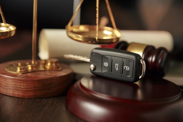 A picture of a gavel, a legal scale, and a car key.