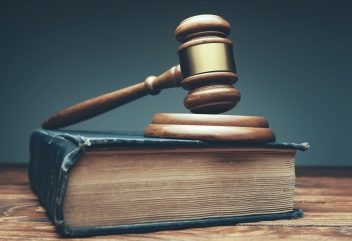 A gavel on a legal book and a desk.