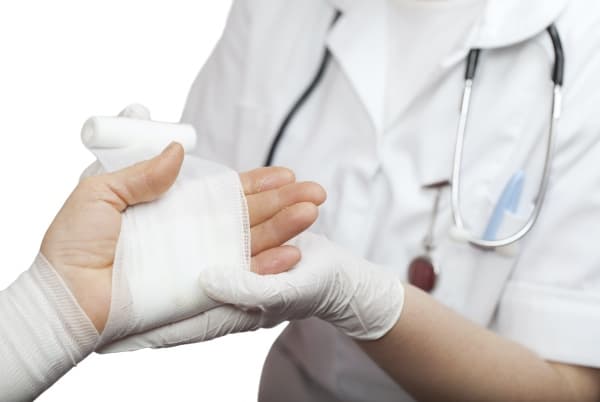 A doctor bandaging a burn injury on the hand.
