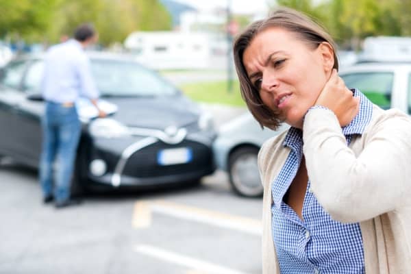 A woman is holding her neck after a car accident.