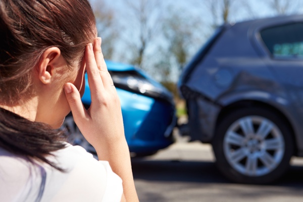 A car accident with an individual holding her head.