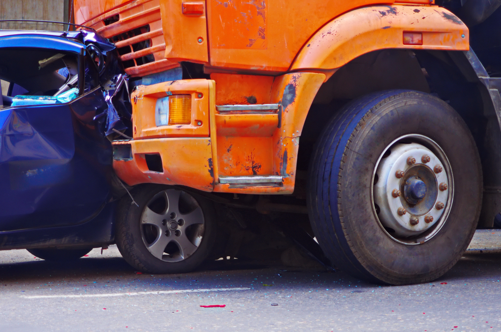 Car with major front-end damage after crashing into the rear of a large truck, showing the severe impact of rear-end collisions