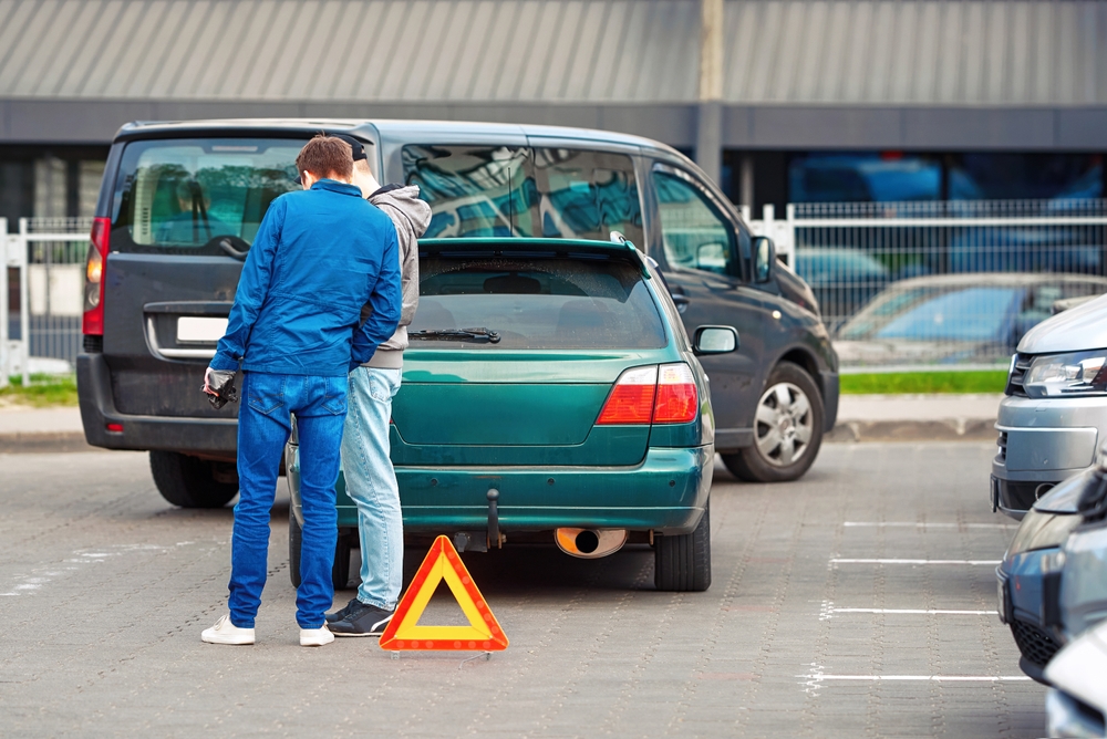 Two drivers looking at a car crash in a parking lot