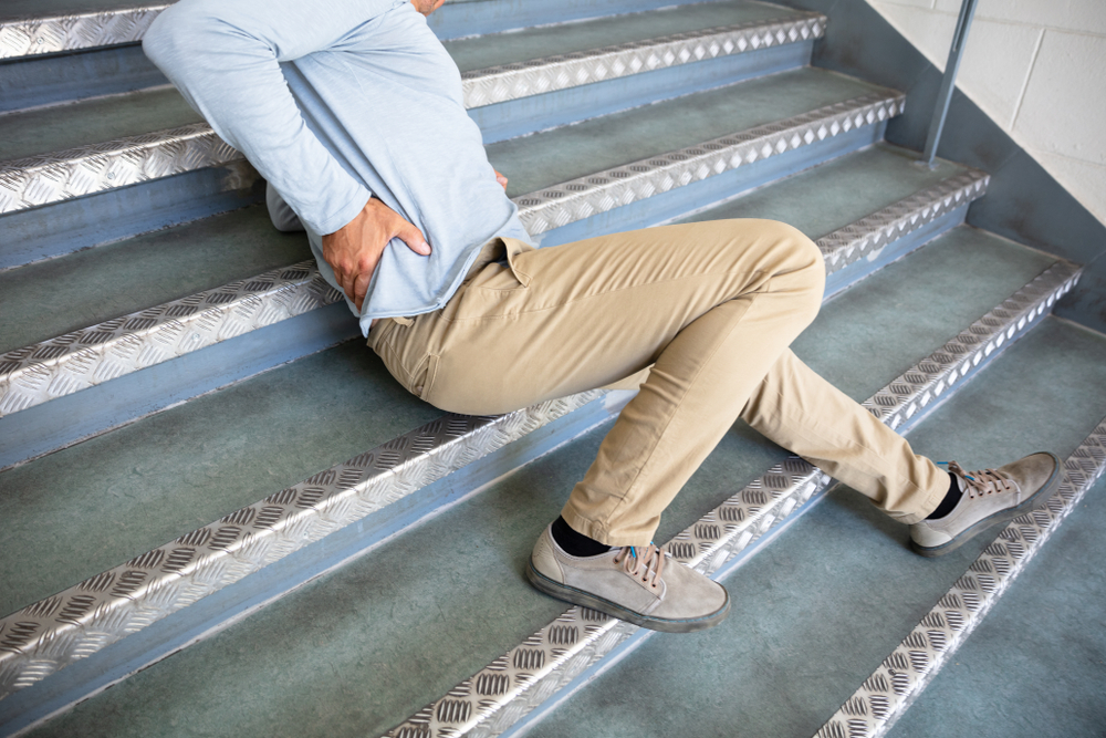 Man holding his back after slipping on stairs, showing common slip and fall injury risk