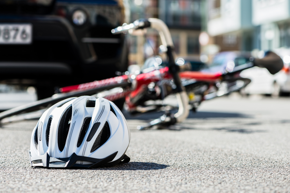 Helmet and bicycle lying on a city street after a collision with a car, illustrating a bike accident scene.