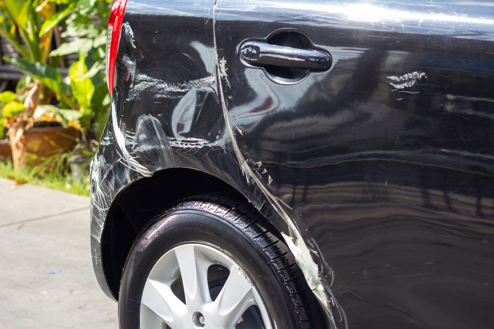 Close-up of a black car with visible scratches and dents after a hit and run accident
