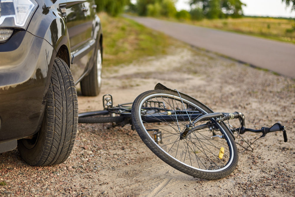 Damaged bicycle lying next to a car on a rural Texas road, symbolizing a collision involving a cyclist.