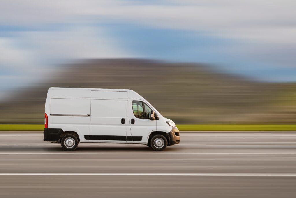 White company van driving on a Texas highway representing work vehicle accident cases.