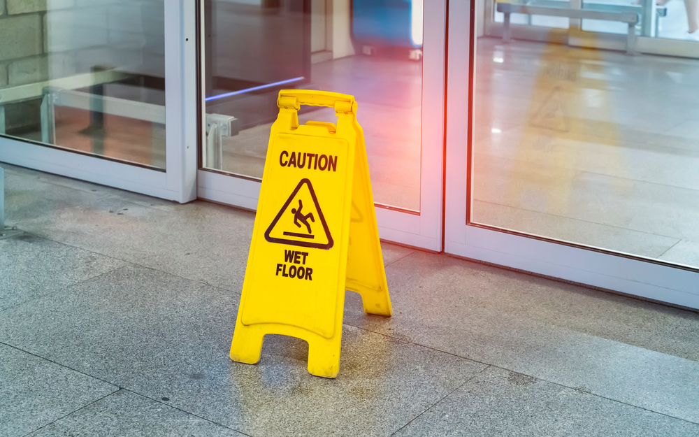 Wet floor caution sign warning visitors of a slipping hazard on commercial property.