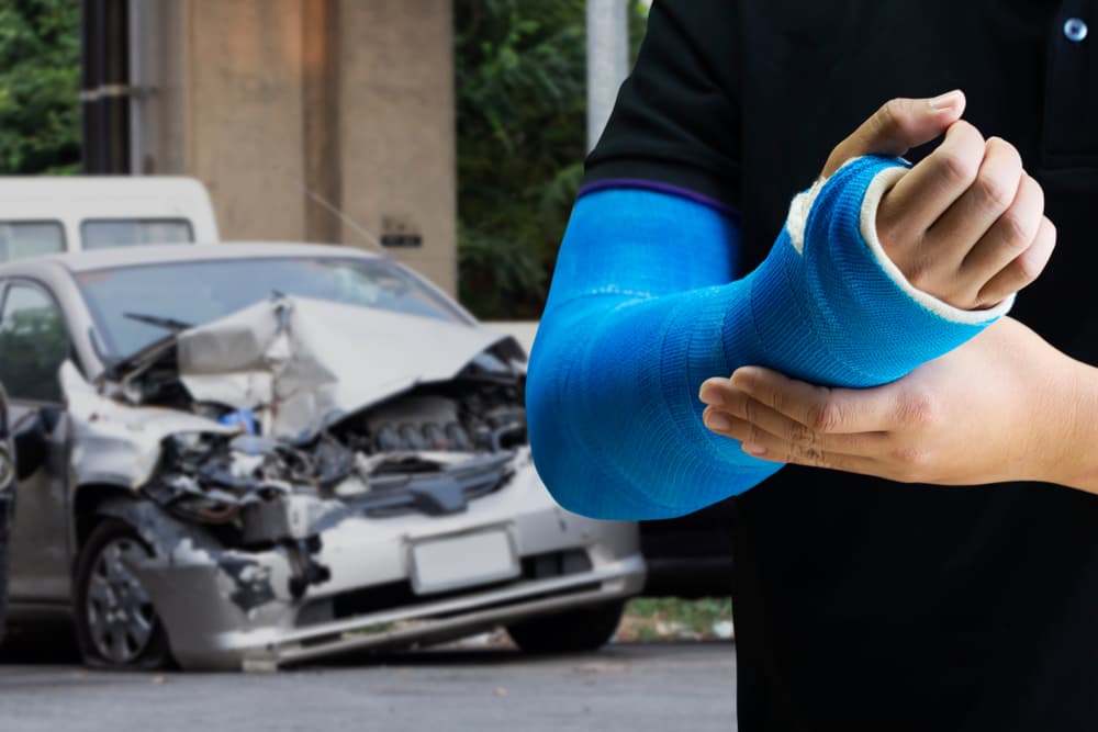 man holding hand with blue bandage as arm injury concept with car accident