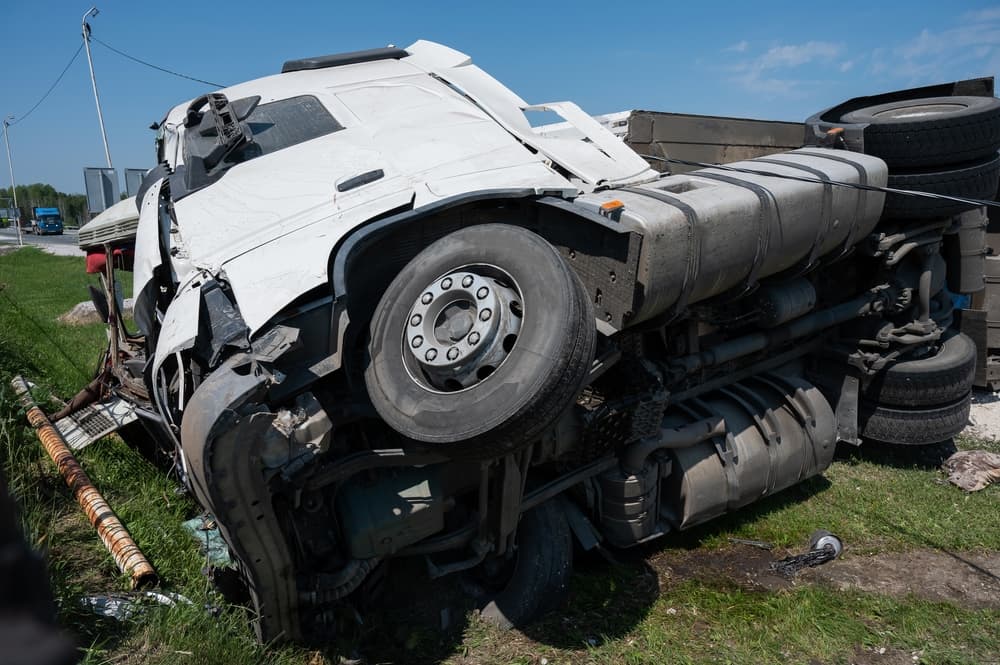 The truck is lying on its side after accident on the highway