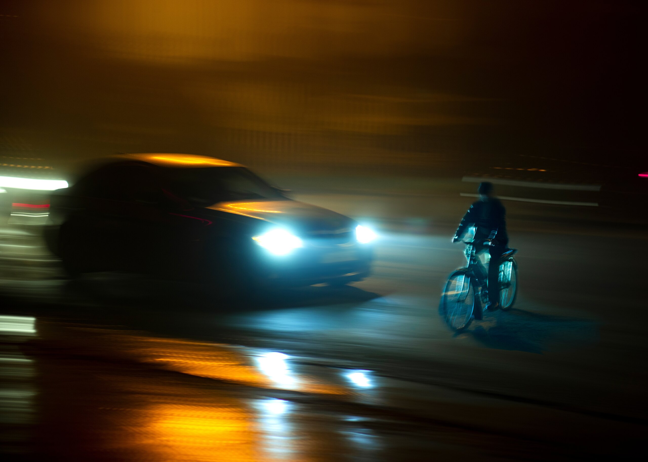 Cyclist riding at night near oncoming vehicle headlights in Arlington, highlighting common safety concerns discussed in frequently asked questions about bicycle accidents.