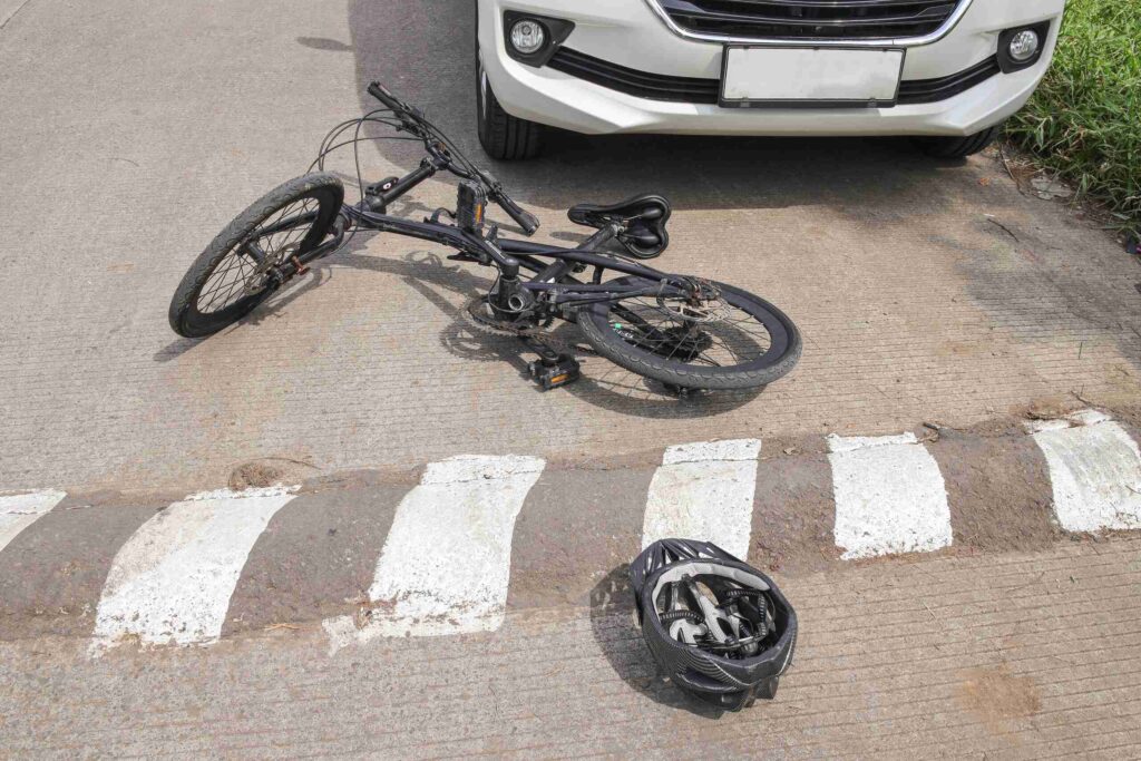 Bicycle and helmet lying on the roadway near a vehicle after a collision in Arlington, related to frequently asked questions about bicycle accidents and liability.