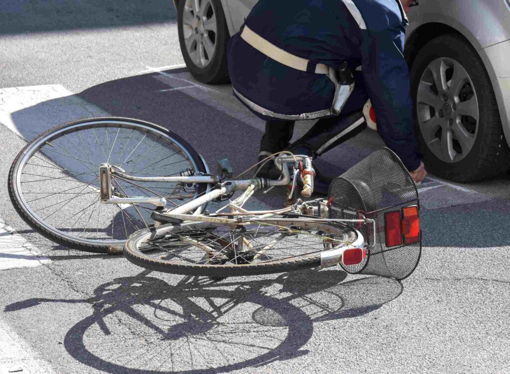 Police officer inspecting a damaged bicycle after a traffic collision in Arlington, addressing frequently asked questions about bicycle accidents and legal claims.