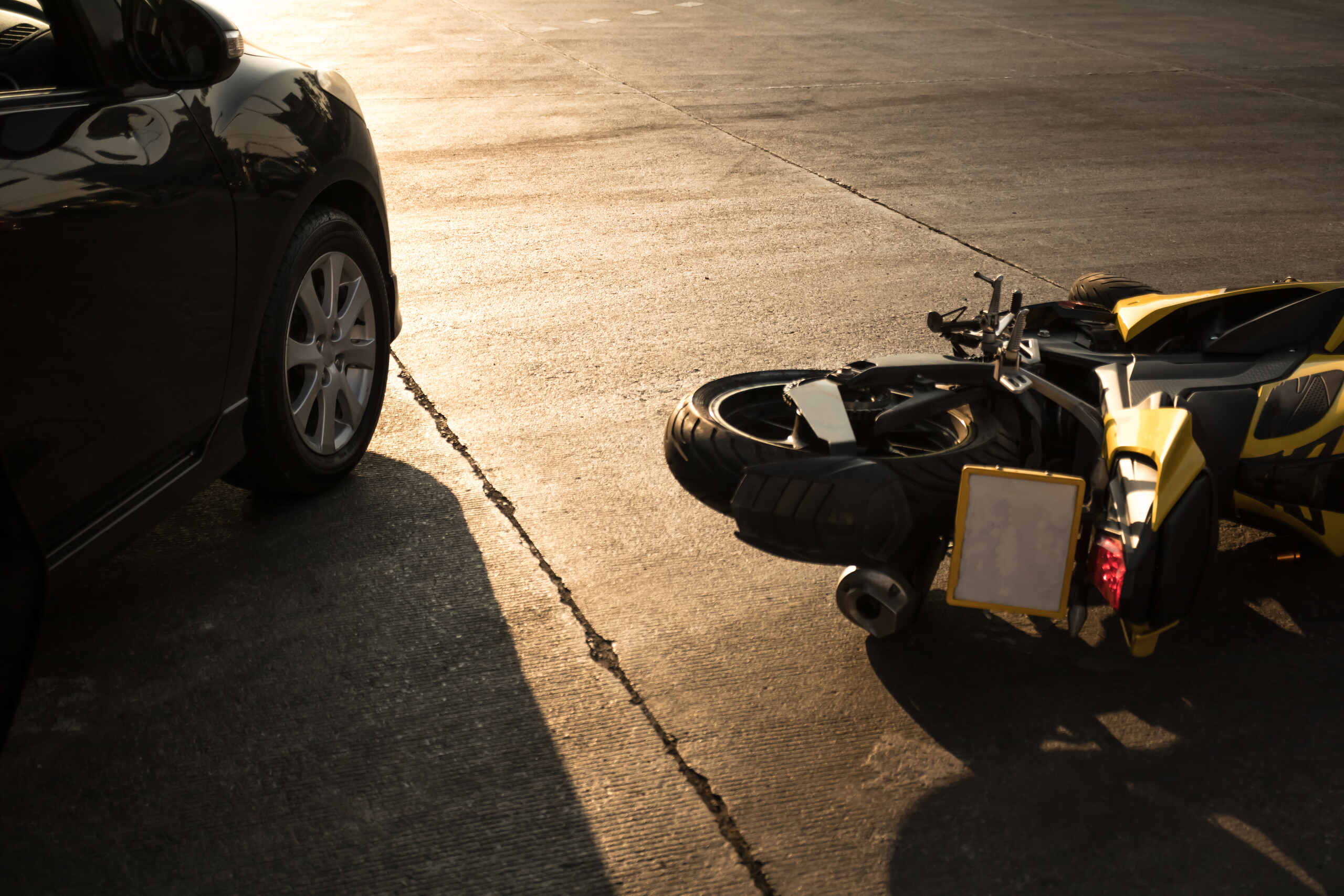 A yellow motorcycle lying on the pavement after a collision in Arlington, TX, reflecting motor vehicle accident statistics for high-risk urban areas.