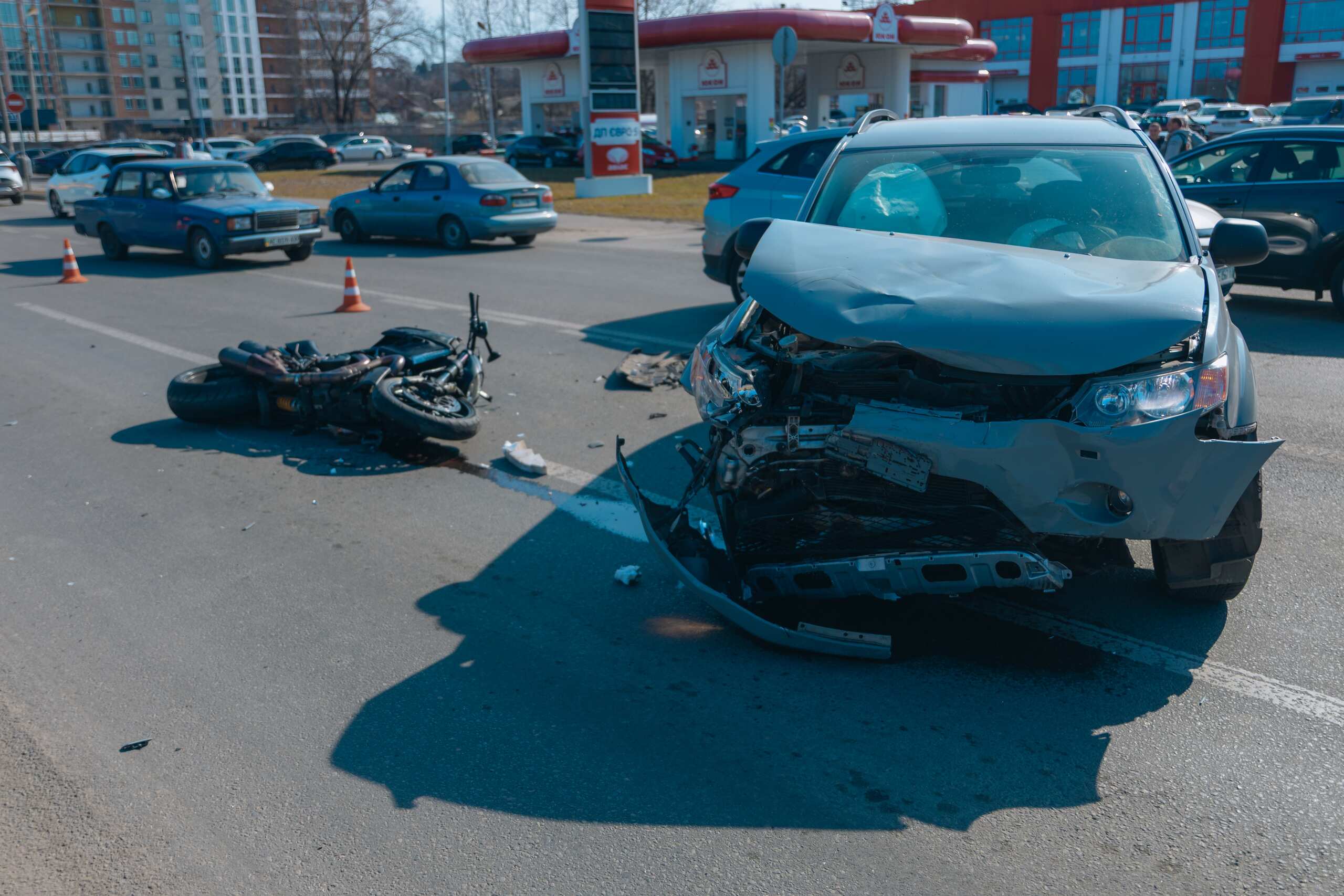 A gray SUV with severe front-end damage next to a downed motorcycle, demonstrating common types of car accidents in Texas.