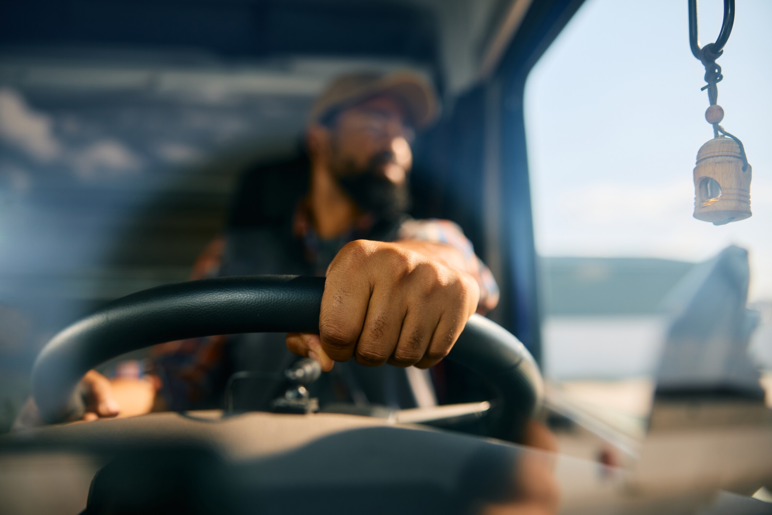 A close-up of a truck driver’s hands on the steering wheel, illustrating common ways driver negligence causes accidents in Texas.