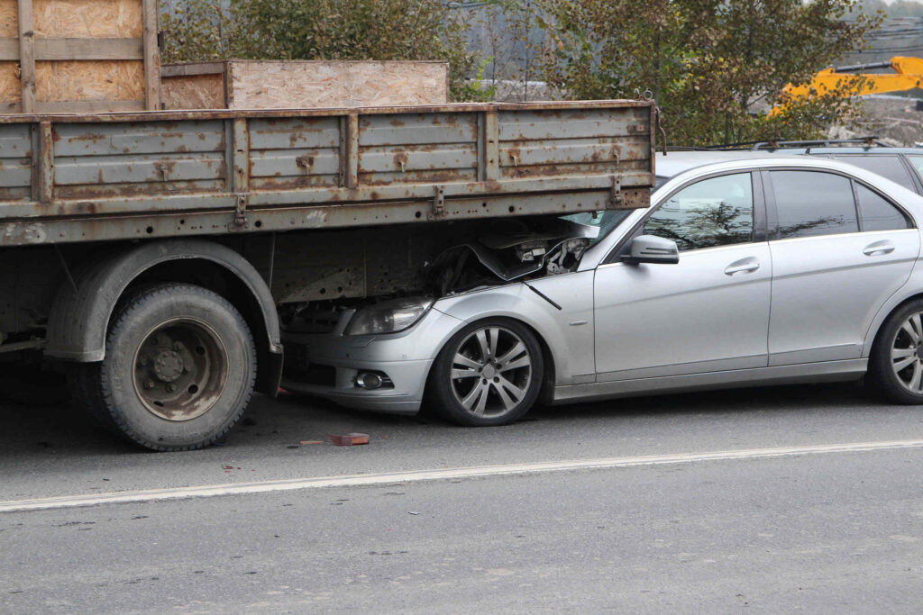 A passenger car wedged underneath the side of a large trailer, representing a Texas underride truck accident.