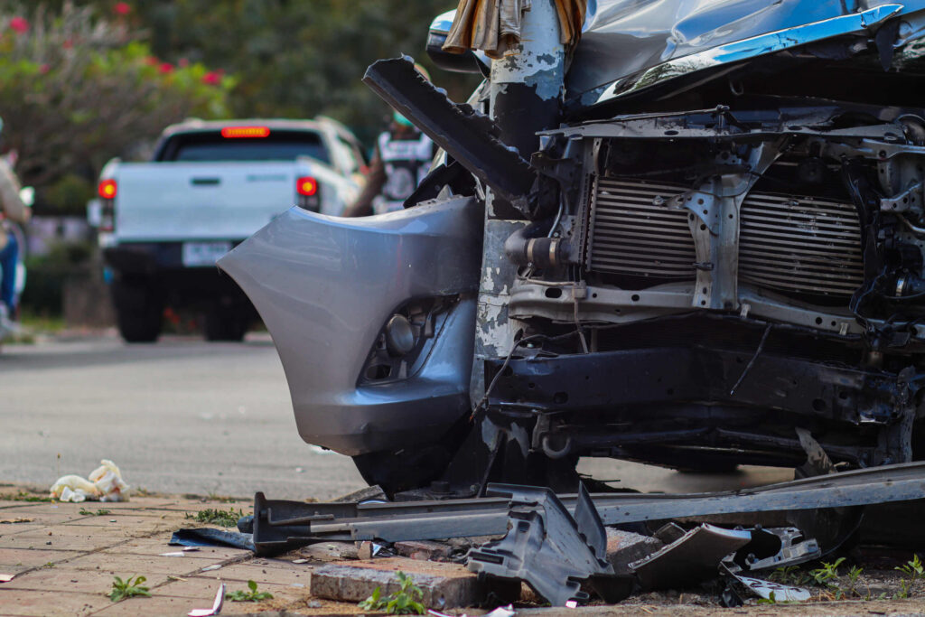 The crushed front end of a passenger vehicle wrapped around a pole following a fatal collision with a truck.