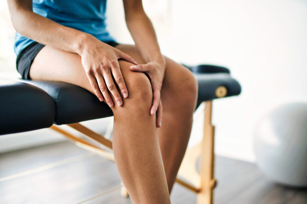 A person holding their injured knee during a medical examination, illustrating physical damages in a Texas personal injury claim.