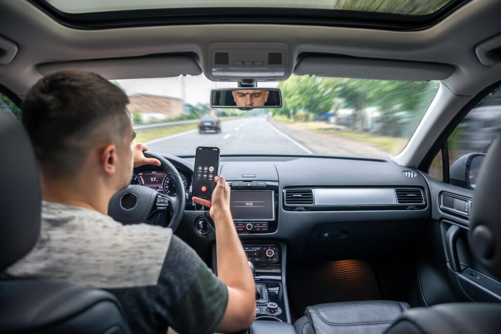 Motorist looking at a cellphone while driving on an Arlington roadway, increasing the risk of distracted driving car accidents in Texas