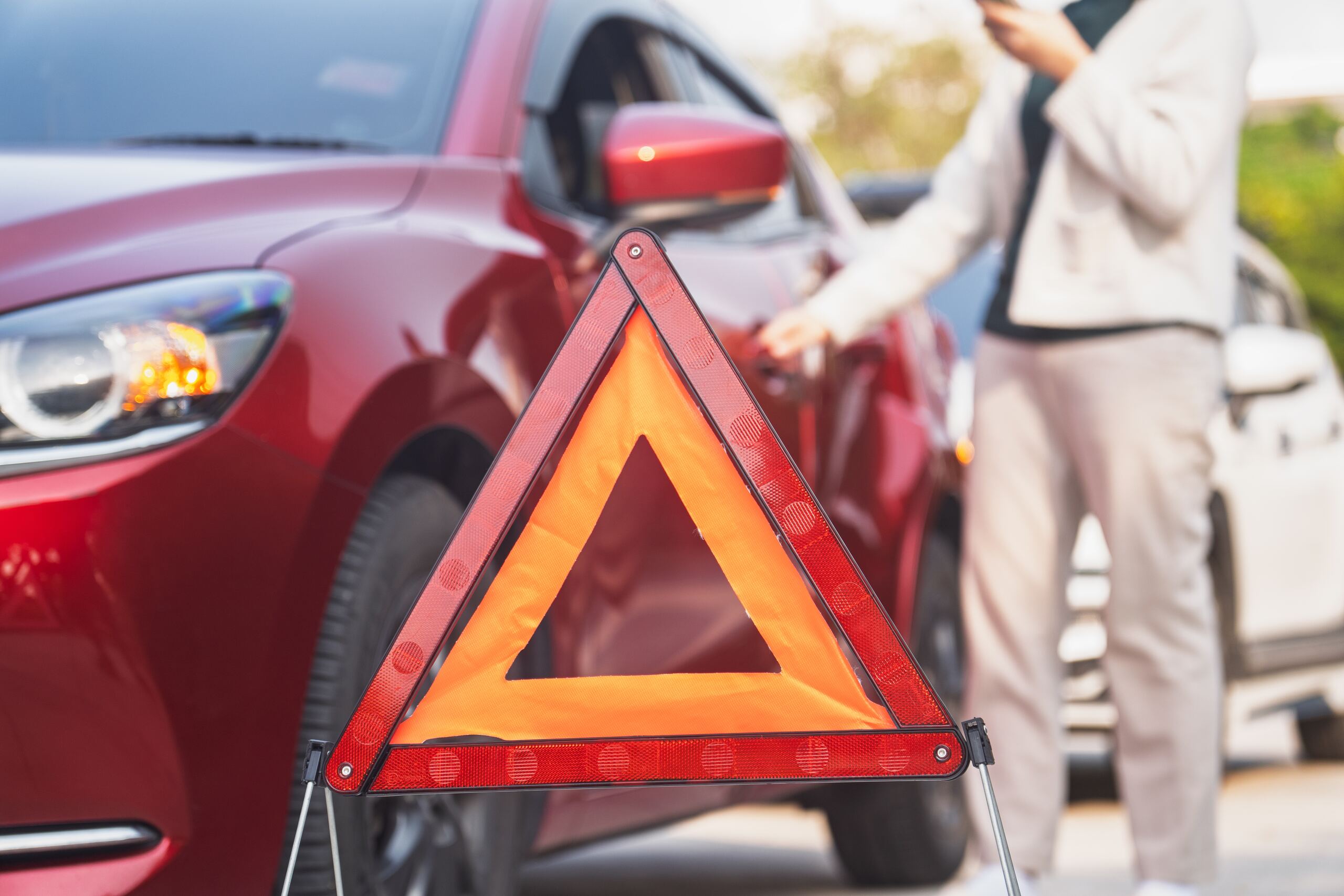 Warning triangle beside damaged vehicle after getting into a car accident in a friend’s car in Texas involving possible insurance and liability issues