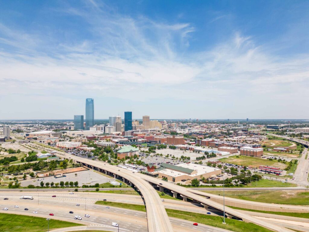 High aerial view of the Oklahoma City downtown skyline and surrounding highway overpasses, providing local geographic context for Oklahoma City Bus Accident Attorneys.