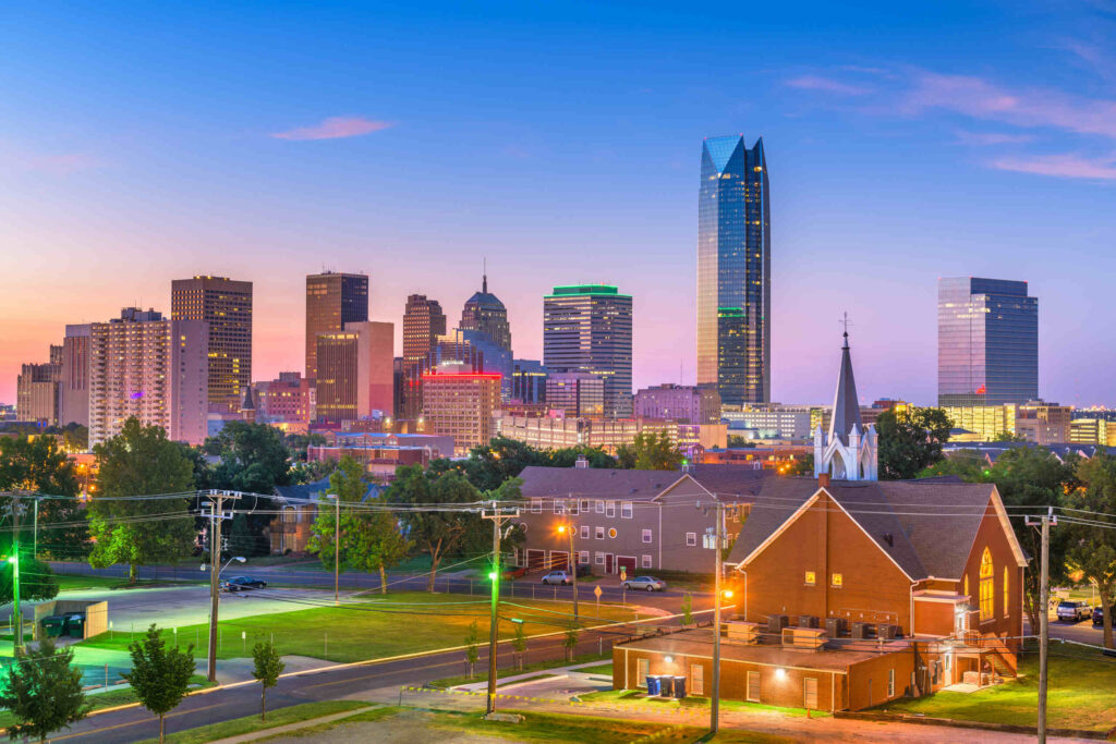 The Oklahoma City skyline at twilight with illuminated buildings and a church in the foreground, providing local context for Oklahoma City Drunk Driving Accident Attorneys.