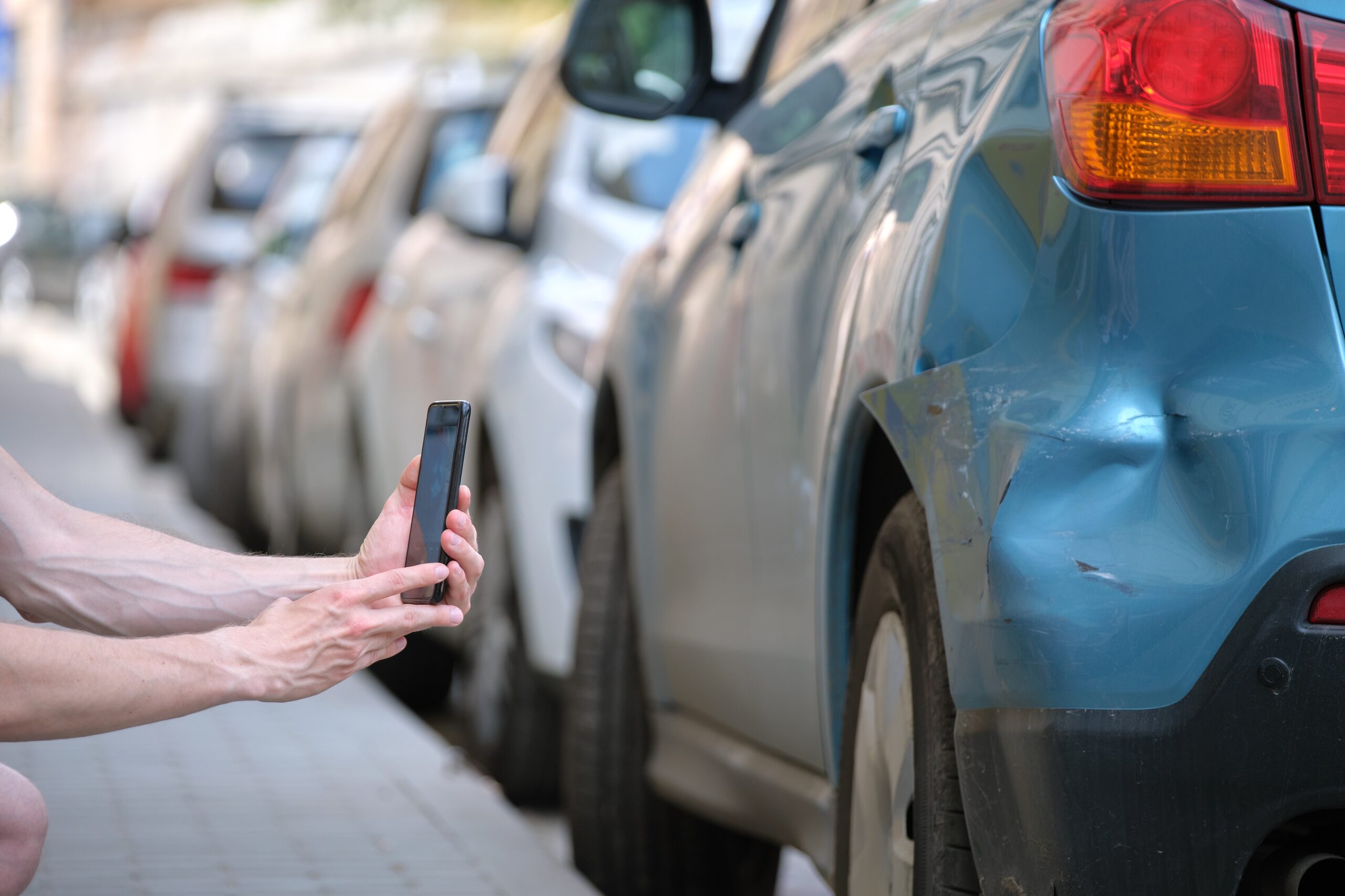 Driver taking photo of car damage for Oklahoma City hit and run accident lawyers.