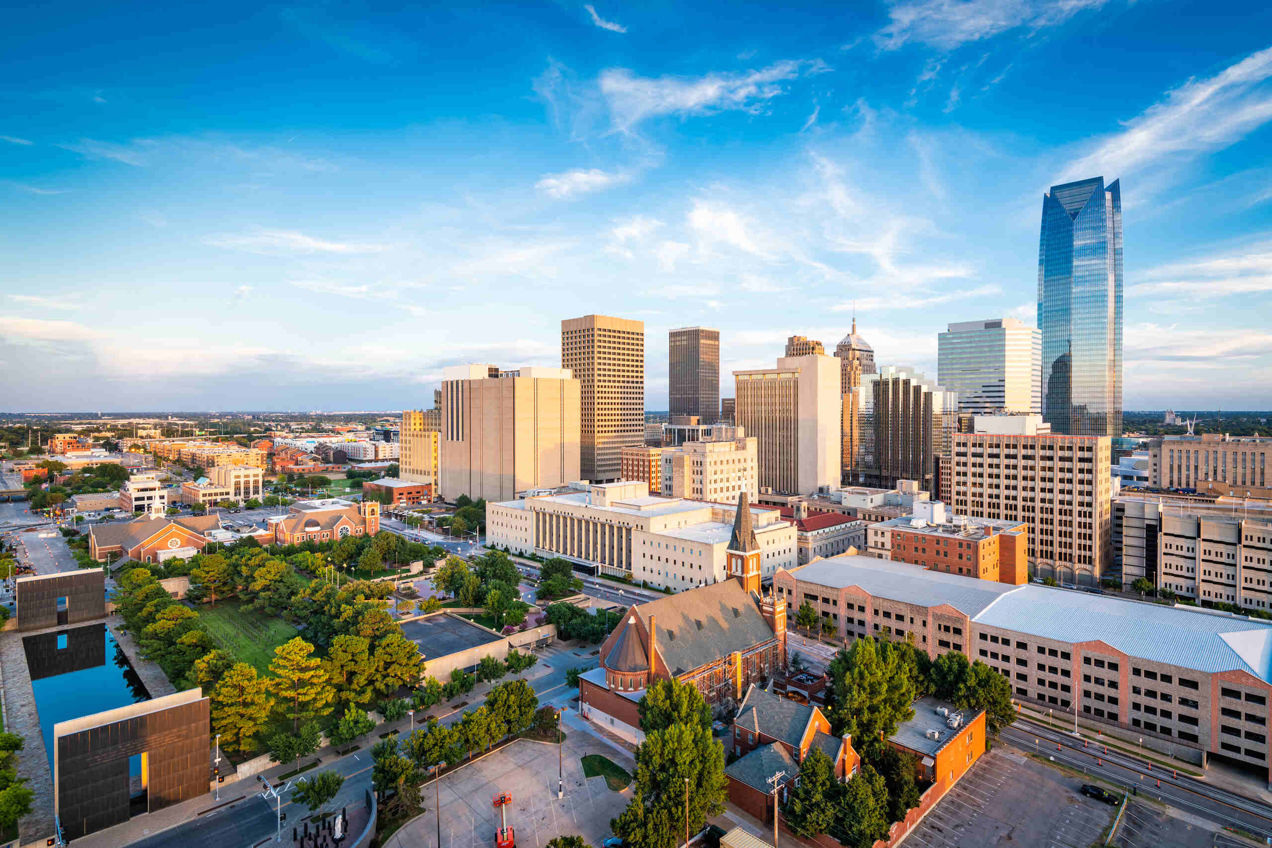 High-angle aerial view of the Oklahoma City skyline under a bright blue sky, providing geographical context for Oklahoma City Motorcycle Accident Attorneys.