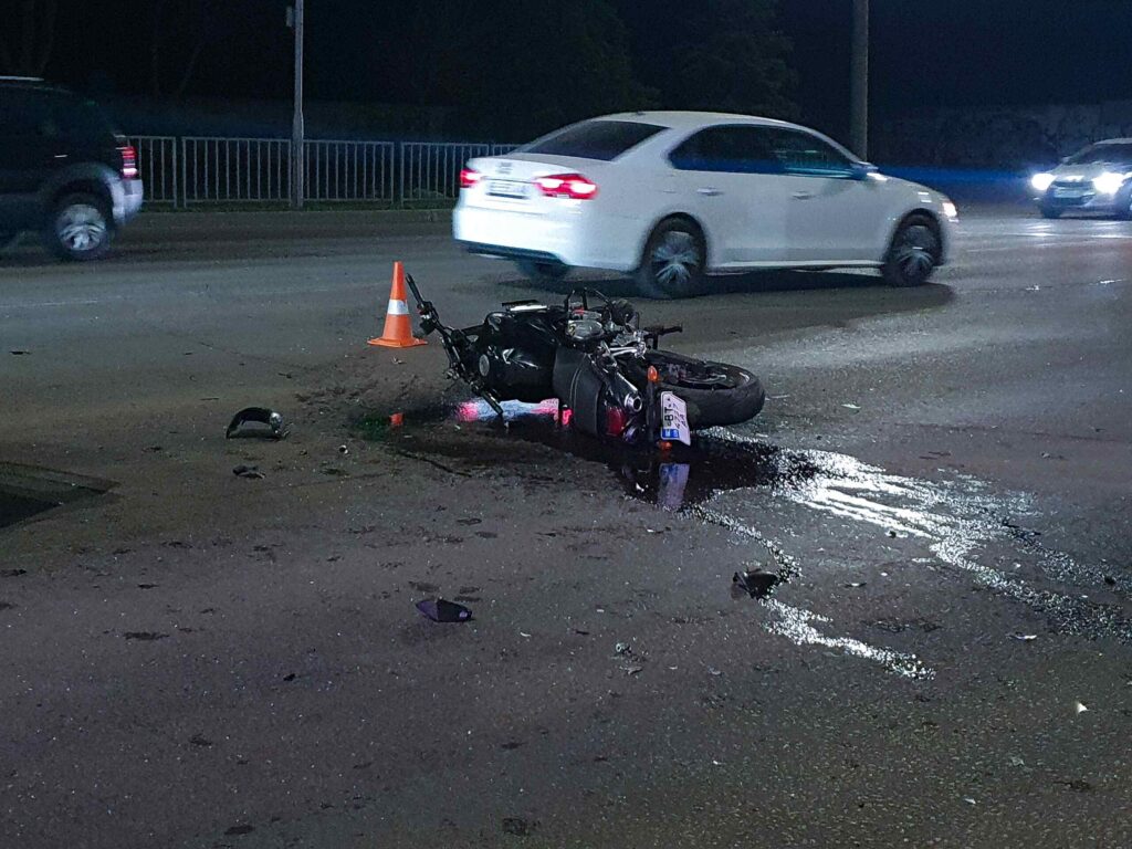 A wrecked motorcycle lying on its side on a city street at night near an orange traffic cone, illustrating case types handled by Oklahoma City Motorcycle Accident Attorneys.