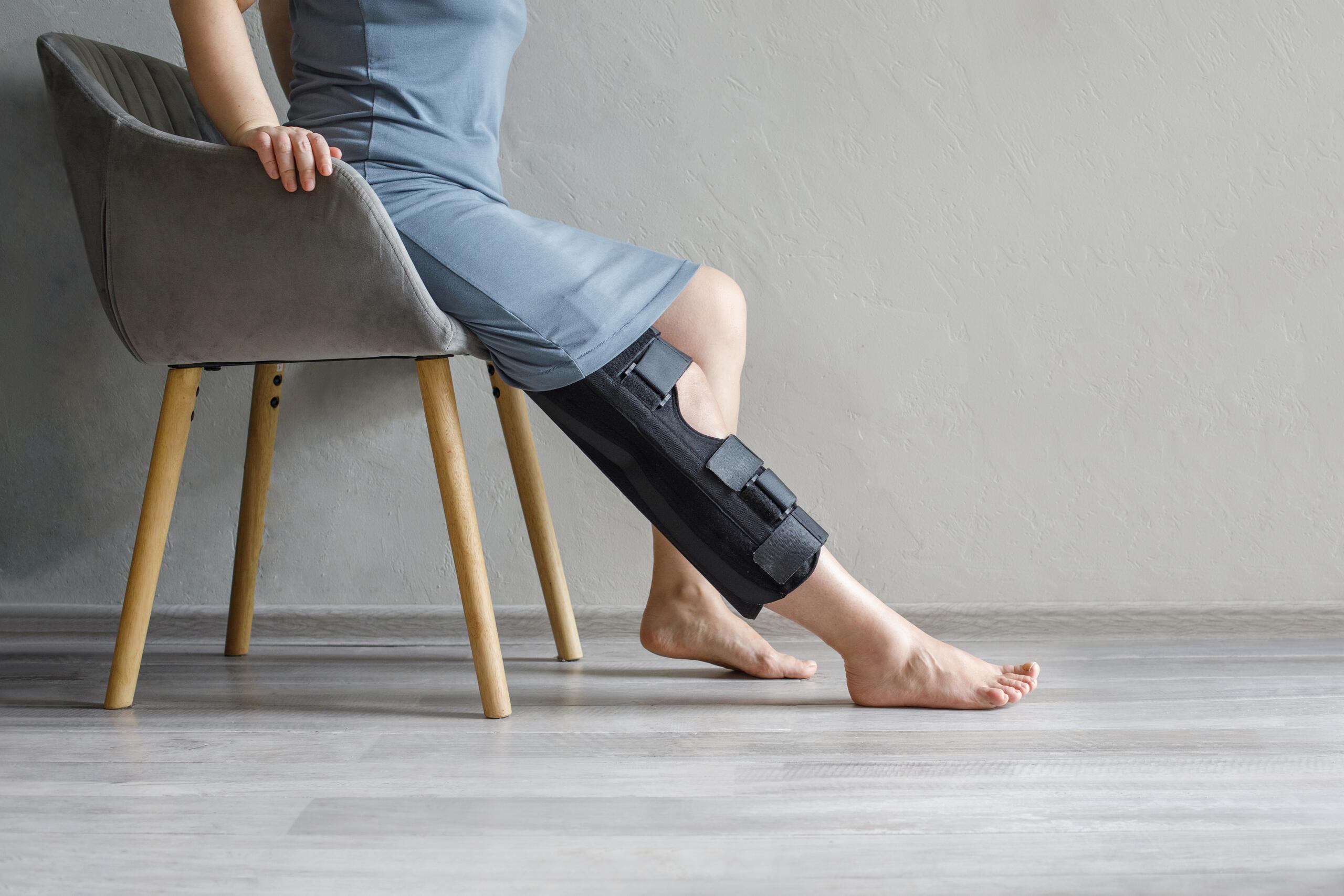 A person wearing a black leg brace while sitting on a chair, illustrating personal injury cases handled by Oklahoma City Pedestrian Accident Attorneys.