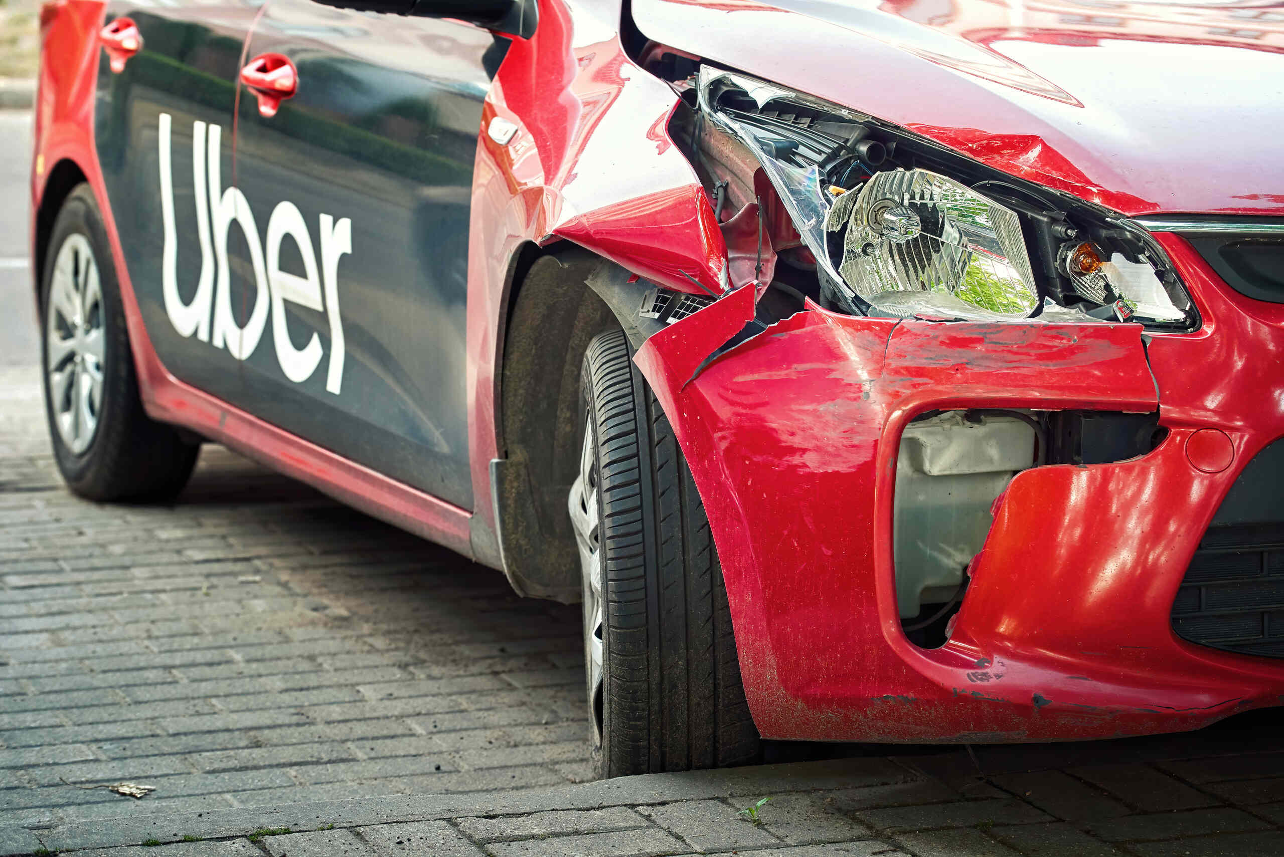 A red car with front-end bumper damage and an Uber logo on the door, illustrating cases handled by Oklahoma City Pedestrian Accident Attorneys.