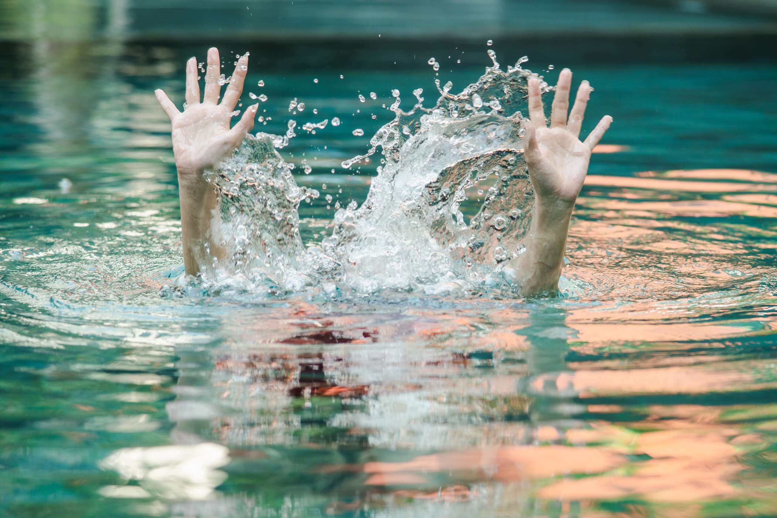 Hands reaching out of splashing water illustrate a drowning emergency handled by Oklahoma City Swimming Pool Accident Lawyers.