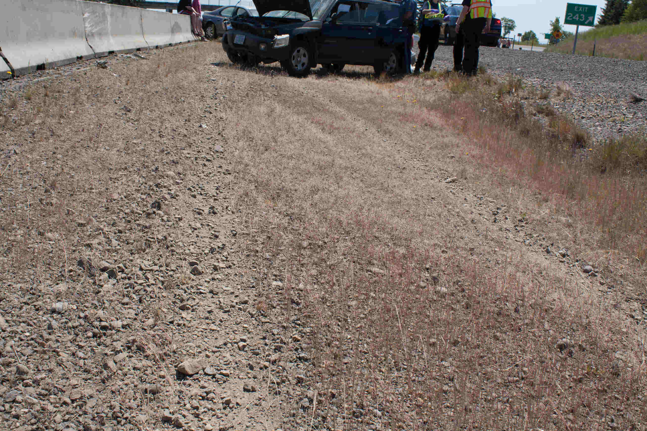 Officers inspecting a vehicle pulled over near a highway shoulder highlights who is liable if a road hazard causes an OKC car accident.