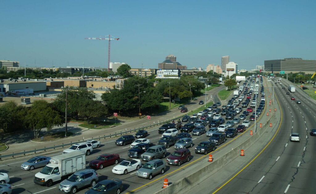 Cars driving beneath highway exit signs pointing toward local routes highlights where do car accidents most occur in Oklahoma City.