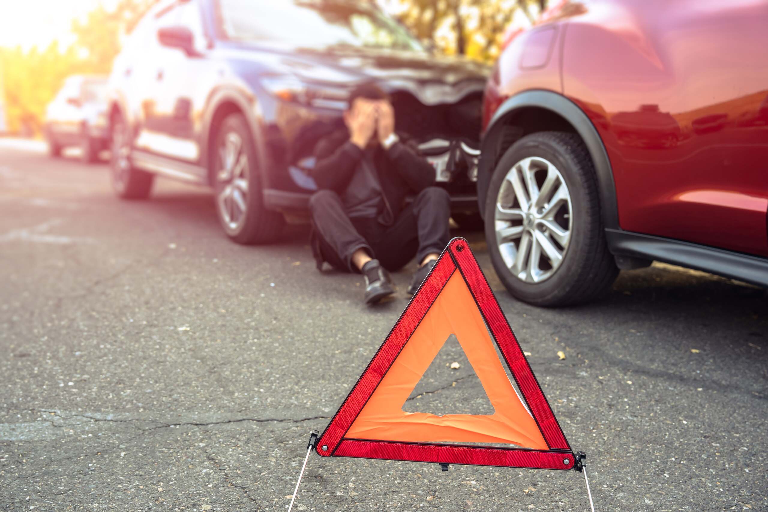 A driver sitting in distress behind a collision warning sign illustrates who is at fault for an Oklahoma City rear-end accident.